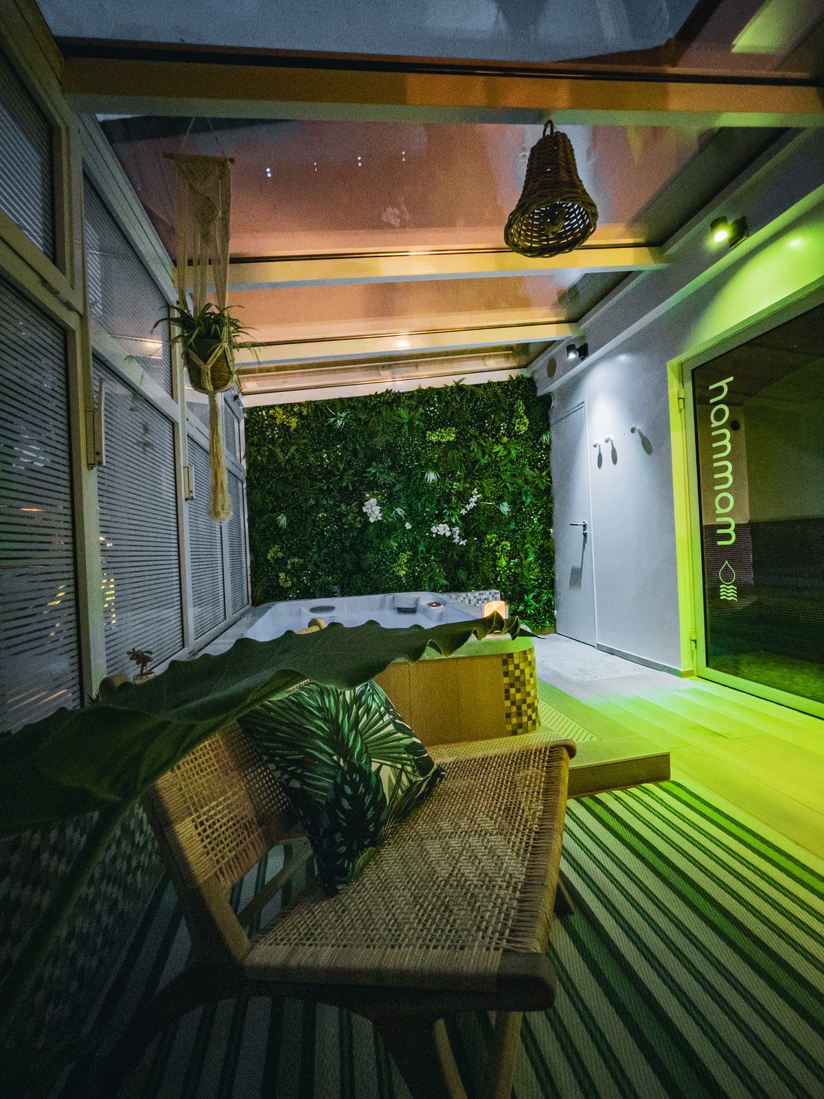 Espace bien-être de la Maison Altruiste : bain bouillonnant, mur végétal et entrée du hammam dans une ambiance tamisée